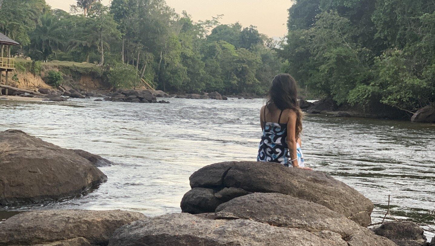 Suriname and beyond sitting on a rock in the river boven Suriname